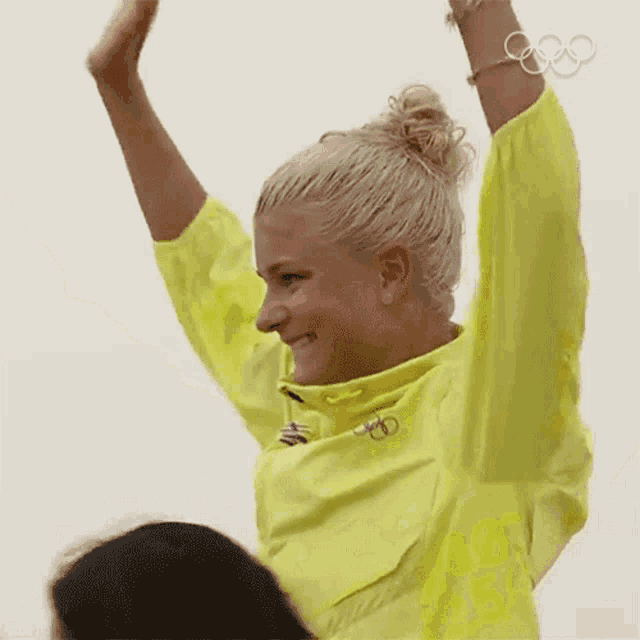 a woman in a yellow jacket with the olympic rings on her arm