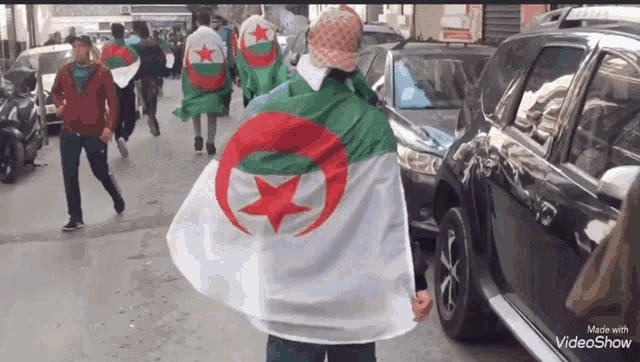 a group of people walking down a street with flags on their backs made by videoshow