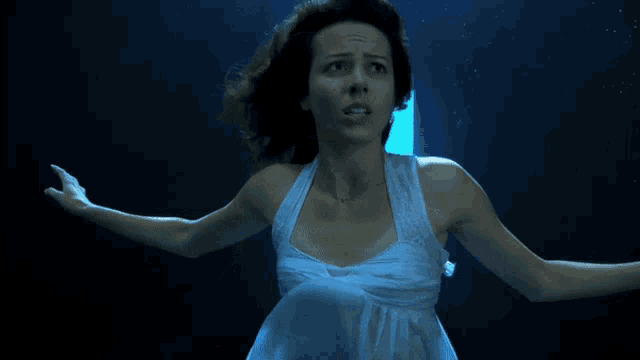 a woman in a white dress is swimming in the dark