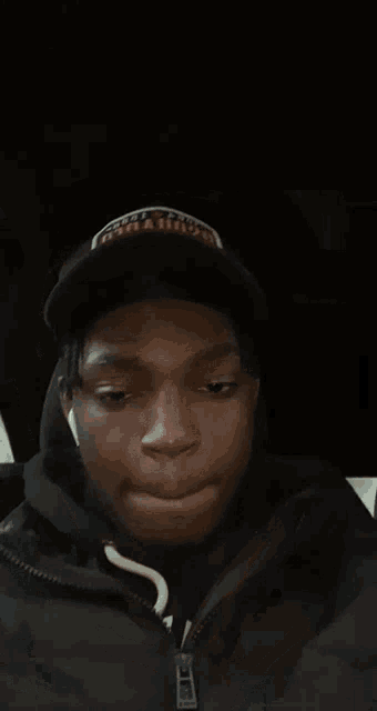 a man wearing a hat and headphones is sitting in a car with his eyes closed .