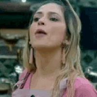 a close up of a woman wearing a pink shirt and earrings looking up .