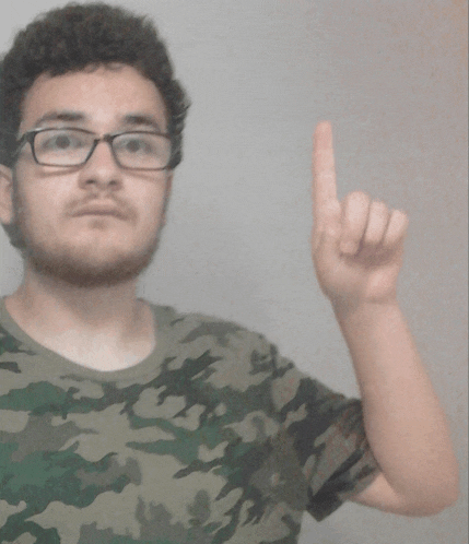 a young man wearing glasses and a camo shirt points up