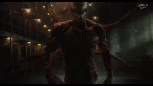 a superhero is standing in a dark room with a huge monster behind him .