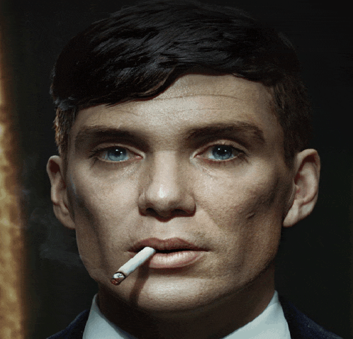 a man with a cigarette in his mouth is looking at the camera