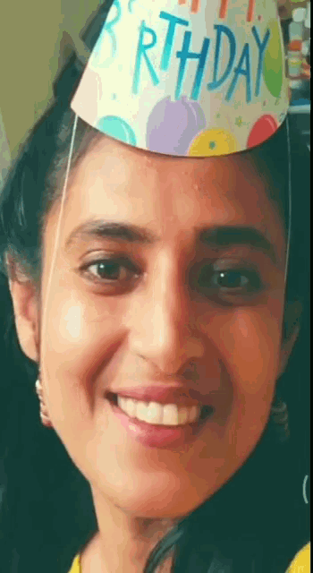 a woman wearing a birthday hat with balloons on it
