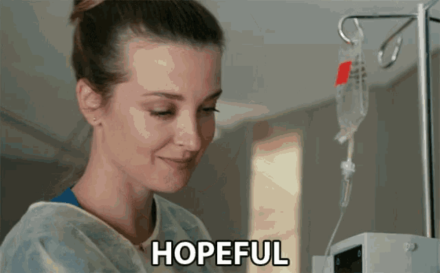 a woman in a hospital gown stands in front of an iv drip and the word hopeful is written below her