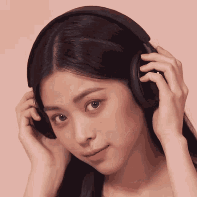 a woman wearing black headphones looks at the camera