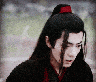 a man with long black hair is wearing a red scarf around his head