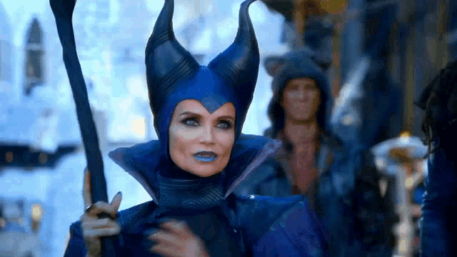 a woman in a blue costume with horns is holding a sword .
