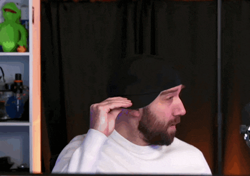 a man wearing a white turtleneck and a black hat