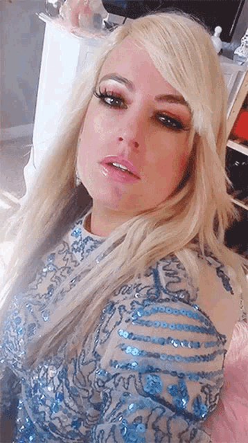 a woman with blonde hair is wearing a blue dress with sequins