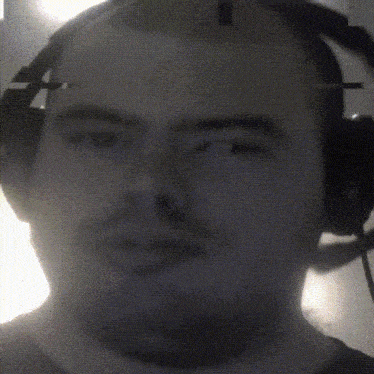 a man wearing headphones looks at the camera with a blurry background