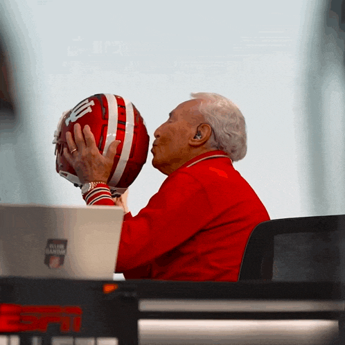a man in a red jacket kisses a football helmet that has the number 10 on it