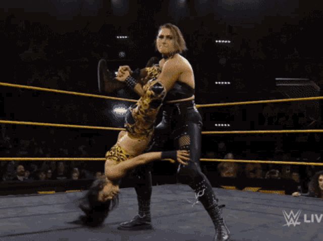 two women are wrestling in a wrestling ring with a w live logo on the bottom