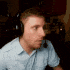 a man wearing headphones and a microphone is sitting in front of a computer screen .