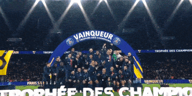 a group of soccer players celebrate in front of a sign that says vainqueur