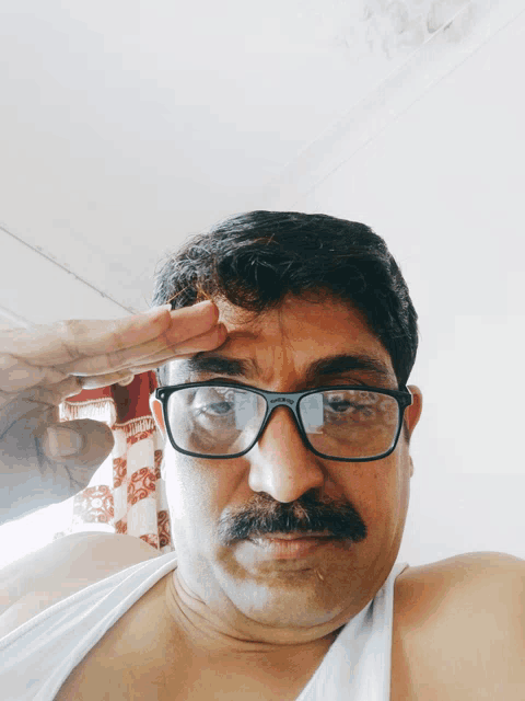 a man wearing glasses and a white shirt salutes