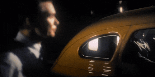 a blurry picture of a man standing next to a car in the dark .