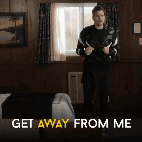 a man is standing in a room with the words get away from me