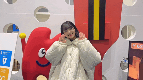 a woman stands in front of a red and yellow sculpture with a sign that says 6:00