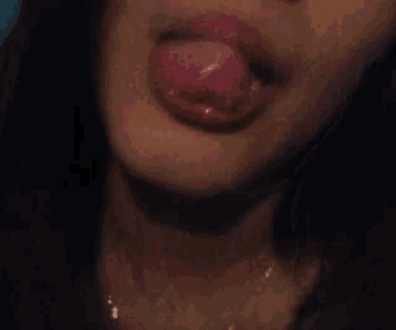 a close up of a woman 's mouth sticking out her tongue .