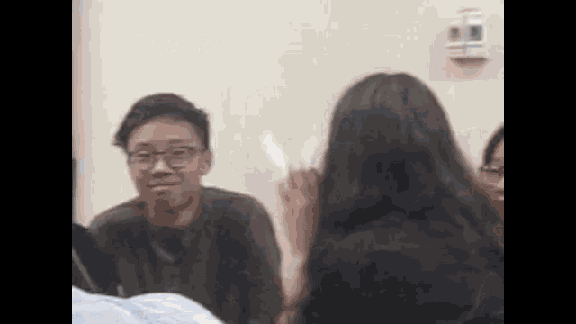 a group of people are sitting in a room and one of them is holding a piece of paper .