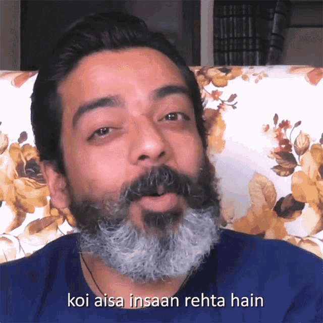 a man with a beard is sitting in a chair with the words koi aisa insaan rehta hain below him