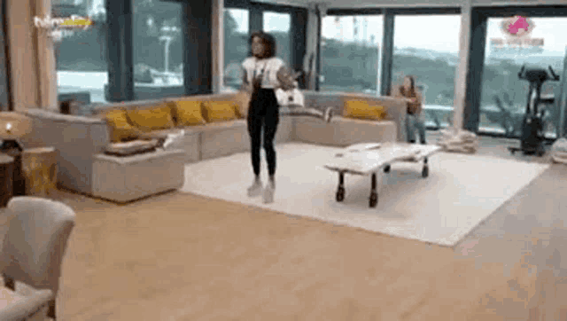 a woman is dancing in a living room with a couch .