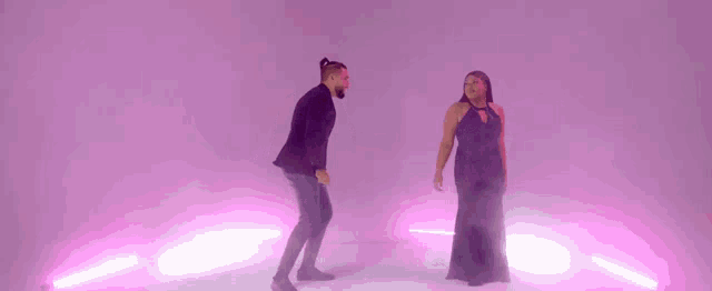a man and a woman are dancing in front of a purple background .
