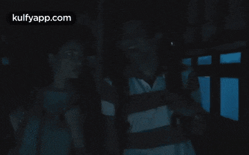 a man and a woman are standing in a dark room and the website kulfyapp.com is on the bottom right