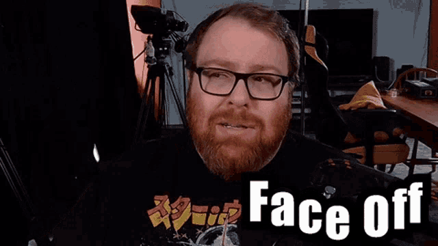 a man with a beard wearing glasses and a shirt that says face off