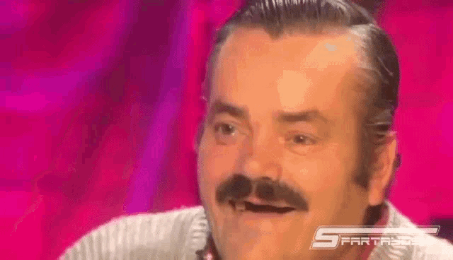 a man with a mustache is making a funny face while sitting on a stage .