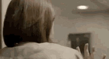 a woman is standing in front of a mirror with her hands outstretched in a room .