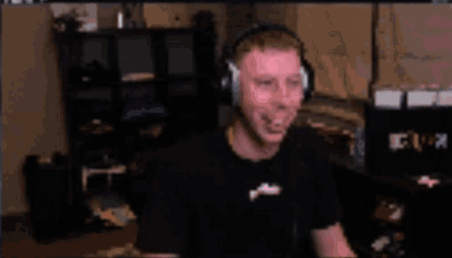 a man wearing headphones is making a funny face in front of a computer screen .