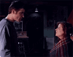 a man putting his hand on a woman 's forehead in a dark room