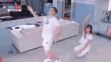 a man and a little girl are dancing in a living room .