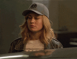 a woman wearing a hat and a leather jacket is looking down