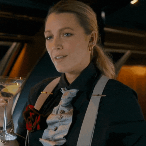 a woman wearing a black shirt and suspenders is holding a martini glass