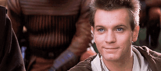 a young man with blue eyes is smiling and looking at the camera .
