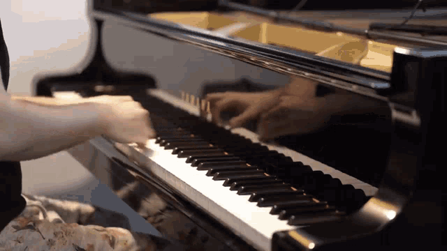 a person playing a piano with a reflection of their hands