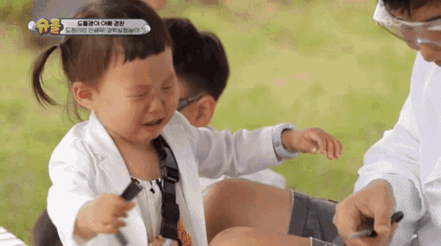 a little girl in a lab coat is crying while playing with a toy