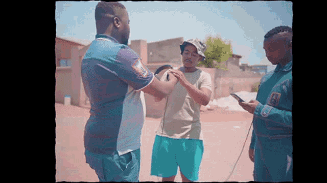 a man in a blue shirt with the letter a on it talks to two other men