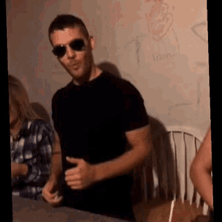 a man wearing sunglasses and a black shirt is giving a thumbs up sign