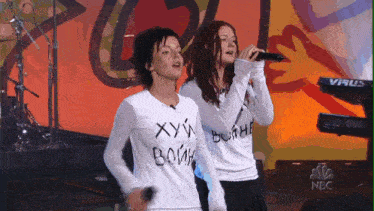 two women are singing in front of a keyboard that says virus on it