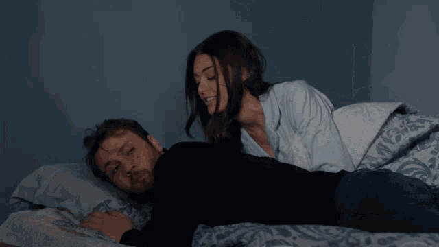 a man laying on a bed with a woman standing behind him