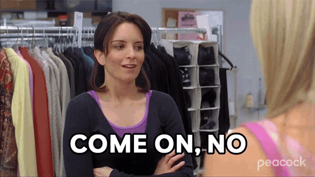 a woman says come on no while standing in front of a rack of clothes