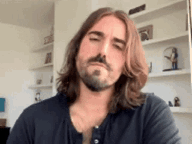 a man with long hair and a beard is wearing a black shirt