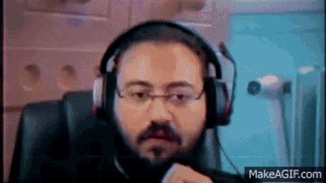 a man wearing headphones and glasses looks at the camera
