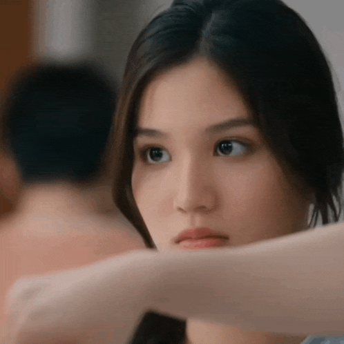 a woman is looking at herself in the mirror while a man is behind her .