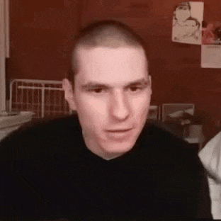 a man with a shaved head is looking at the camera while wearing a black sweater .
